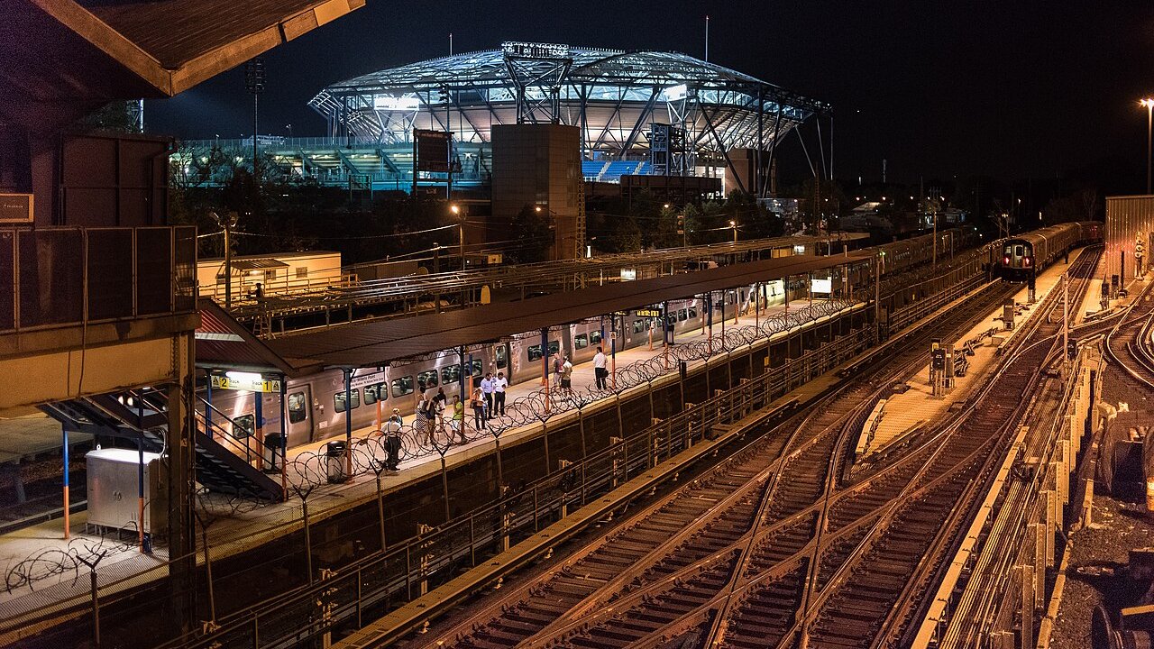 Arthur Ashe Stadium iluminado à noite visto da estação de trem de Flushing Meadows durante o US Open